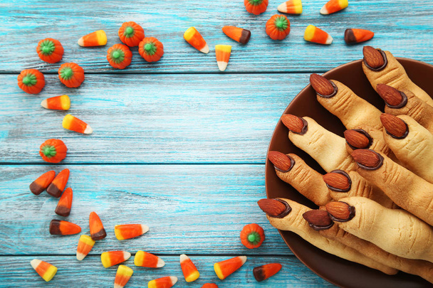 Halloween finger cookies with candies on blue wooden table - Fotó, kép