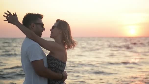 A Couple Hugging and Kissing at the Beach Looking out to the Sea During Sunset. - Video, Çekim