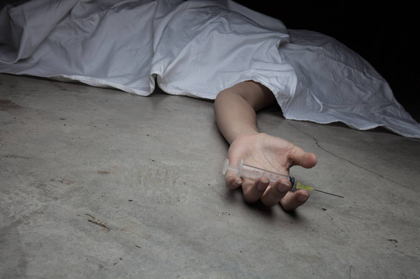 Close-up on the floor of the drugs in hand of the dead body. In the background, a young drug addict - Fotoğraf, Görsel