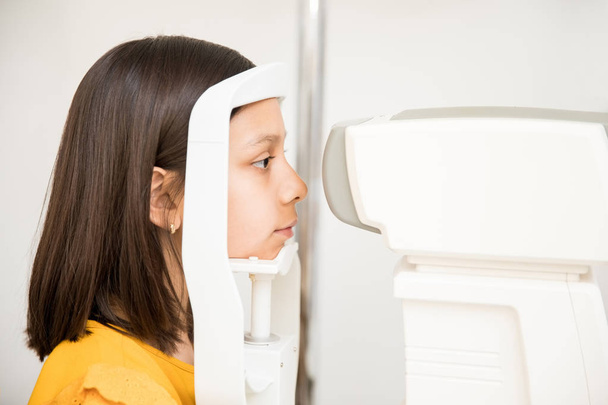 Retrato de close-up de menina bonita tendo teste de visão ocular na clínica óptica
 - Foto, Imagem
