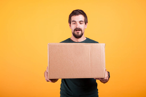 Portrait of handsome young man holding a box in his hands - Photo, Image