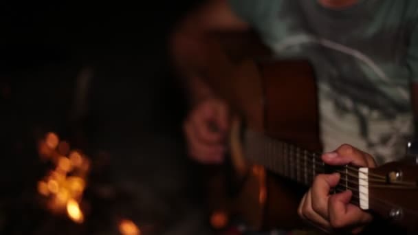 Een man is gitaar spelen. Nacht, vreugdevuur, gitaar. - Video