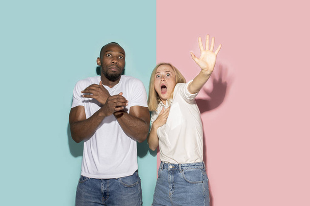 Portrait of the scared couple on pink and blue studio background - Foto, afbeelding
