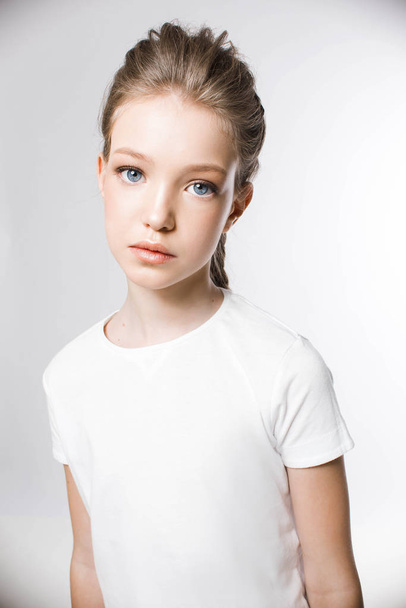 Portrait of young girl in white t-shirt with light makeup and stylish hairstyle on white background - Foto, Bild