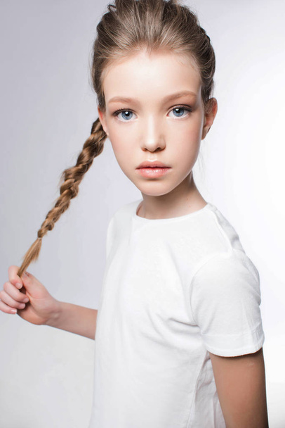 Portrait of young girl in white t-shirt with light makeup and stylish hairstyle on white background - Valokuva, kuva