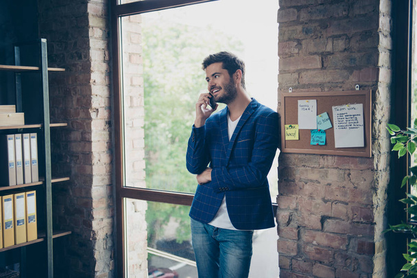 Attractive handsome young brunet bearded smiling executive worker man in office work station work place, talking on the phone - Foto, Imagen