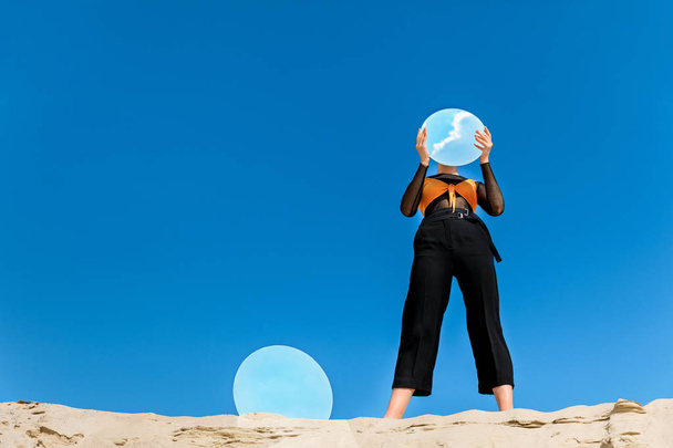 elegantní žena hospodářství zrcadlo s odrazem modré oblohy před čelbou - Fotografie, Obrázek