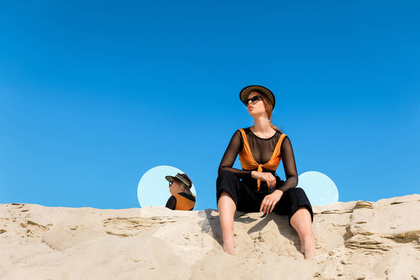 fashionable model posing on sand with round mirrors with reflection of blue sky - Zdjęcie, obraz