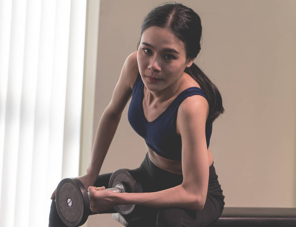 Sterke Aziatische magere vrouw is de opheffing van halter in fitness - Foto, afbeelding