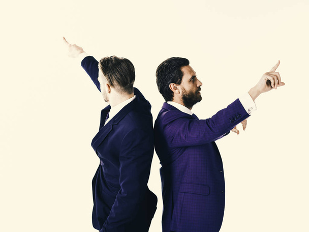 Young businessmen pointing in two different directions at same t - 写真・画像