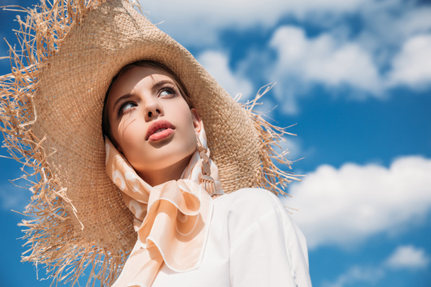 modieuze aantrekkelijk meisje poseren in trendy zijden sjaal en stro hoed - Foto, afbeelding