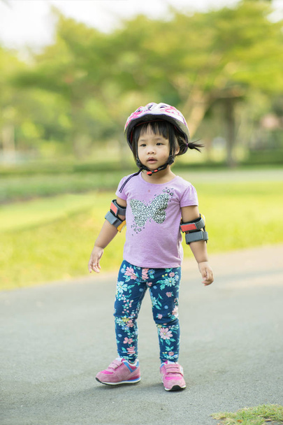 Little girl in cycling wear ready to learn riding balance bike in the park - Foto, Imagen