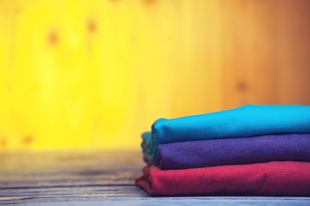 Stack of different cotton t-shirts on wooden table - Foto, imagen