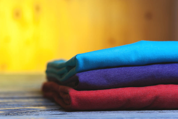 Stack of different cotton t-shirts on wooden table - Photo, image