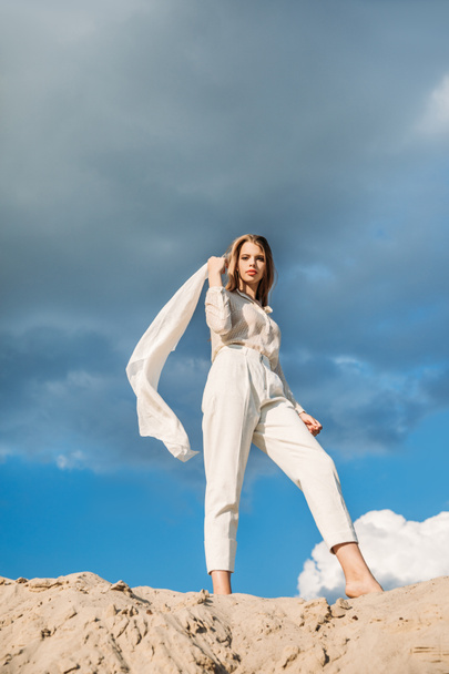 hermosa mujer elegante en ropa blanca con bufanda caminando en la duna de arena
 - Foto, imagen