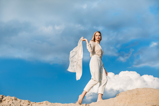 hermosa chica de moda en ropa blanca con bufanda caminando en la duna de arena
 - Foto, imagen