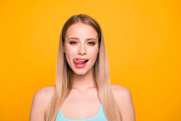 Portrait of happy foolish girl looking camera with tongue out isolated on vivid yellow background - Foto, afbeelding