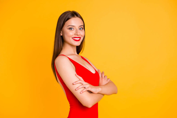 Sweet and charming brunett girl isolated on vivid yellow background with copy space. Confident young woman with big smile stand on half turn and looking at camera crossed her arms over her chest - Фото, изображение