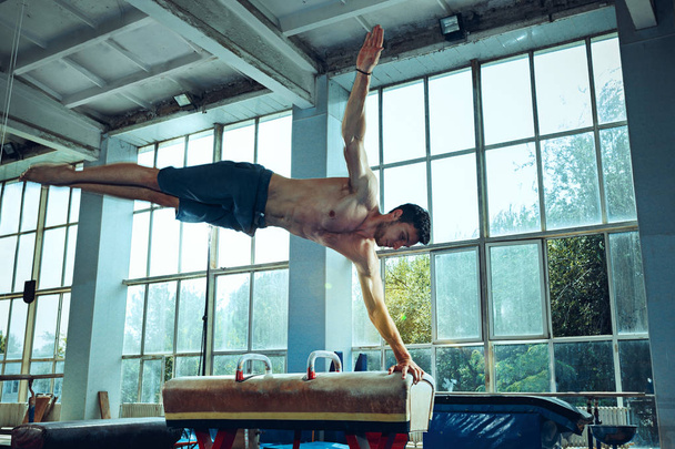 El deportista durante el ejercicio difícil, la gimnasia deportiva
 - Foto, Imagen
