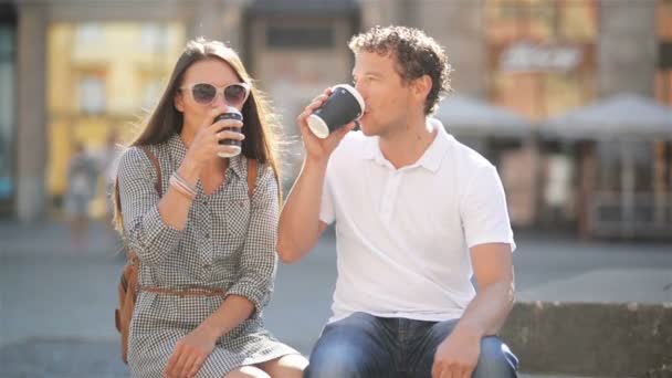 Outdoors Portrait of Happy Couple Drinking Coffee Sitting on the Bench on the City Square During Sunny Summer Day. - Кадры, видео
