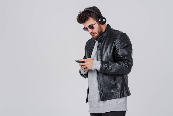 Portrait of young handsome man with headphones and smartphone on gray background - Φωτογραφία, εικόνα