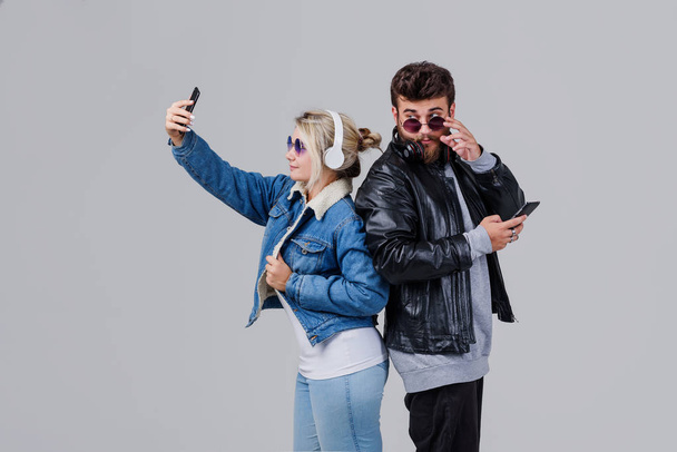 Portrait of a young couple enjoying music and make selfie over grey background - Valokuva, kuva