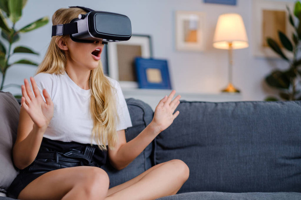 Attractive young woman in VR headset gesturing and smiling - Photo, image