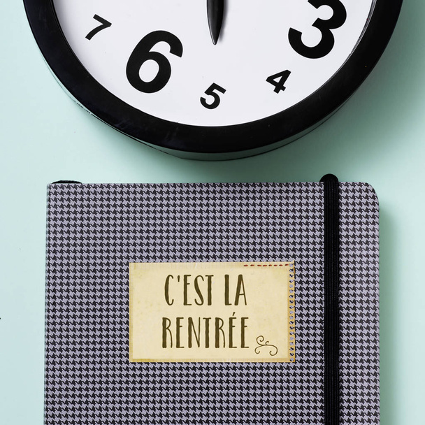 Detailní záběr na hodiny a Poznámkový blok se textu c est la rentree, zpátky do školy v francouzština, na zeleném pozadí - Fotografie, Obrázek