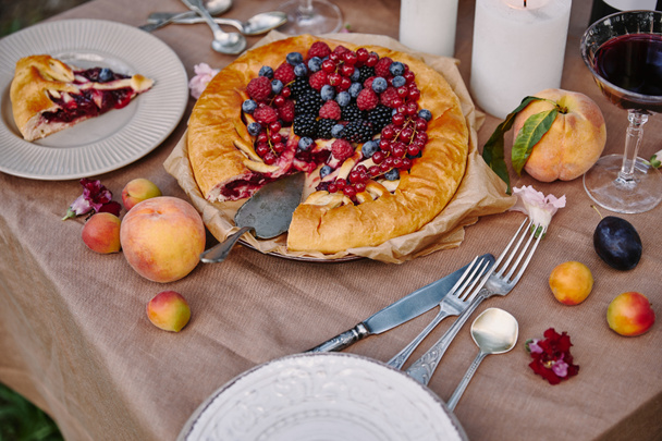 tasty appetizing berries pie and fruits on table in garden - 写真・画像