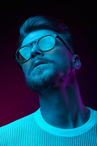Neon light studio portrait of man model with mustaches and beard in sunglasses and white t-shirt  - Φωτογραφία, εικόνα