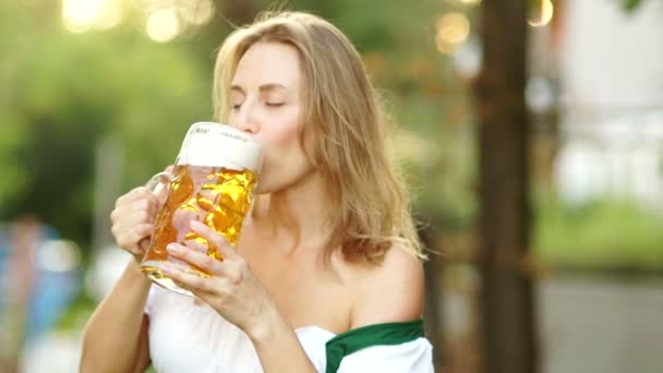 Пивной фестиваль Октоберфест. Девушка в традиционном баварском костюме пьет пиво и неловко вытирает пену о губы. Красные губы, сексуально, эротично
 - Кадры, видео