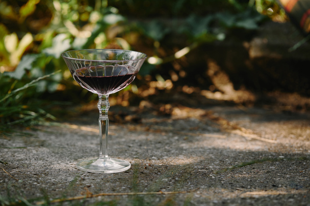 um copo de vinho tinto na estrada no jardim
 - Foto, Imagem