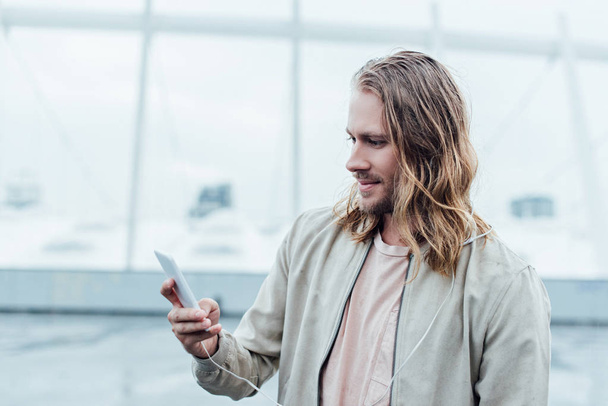 handsome young man using smartphone on street on cloudy day - Photo, Image