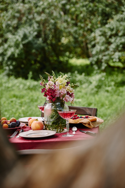 bouquet of flowers and fruits on table in garden - Foto, afbeelding