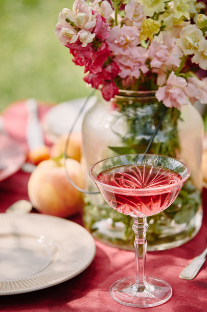 wineglass and bouquet of flowers on table in garden - Photo, Image