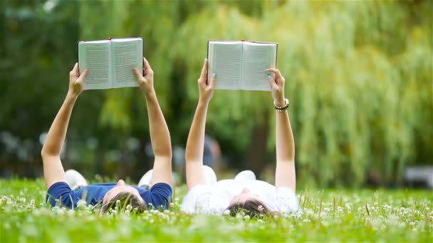 Uvolněné mladý pár čtení knih vleže na trávě - Záběry, video