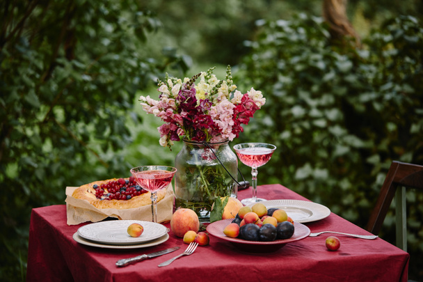 bouquet de fleurs en pot de verre et verres à vin sur la table dans le jardin
 - Photo, image