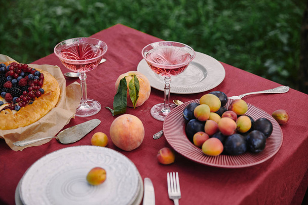 glasses of wine, berries pie and fruits on table in garden - Foto, Imagen