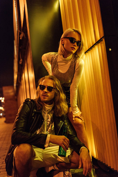 young attractive couple in fashionable clothes on night street under yellow light - Foto, Imagem