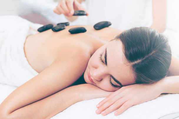 Žena dostává masáž horkými kameny od profesionálního kosmetického terapeuta v lázeňském salonu. Luxusní wellness, úleva od stresu zad a koncept omlazení. - Fotografie, Obrázek