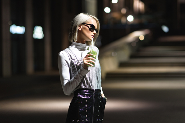 attraktive junge Frau mit Mojito im Plastikbecher auf dunkler Straße - Foto, Bild