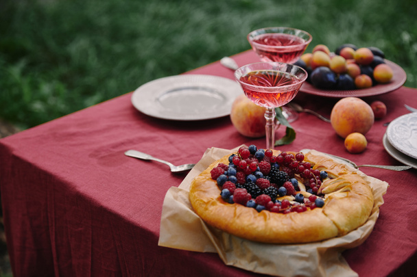 ベリーのパイと庭のテーブルでワインのグラス - 写真・画像