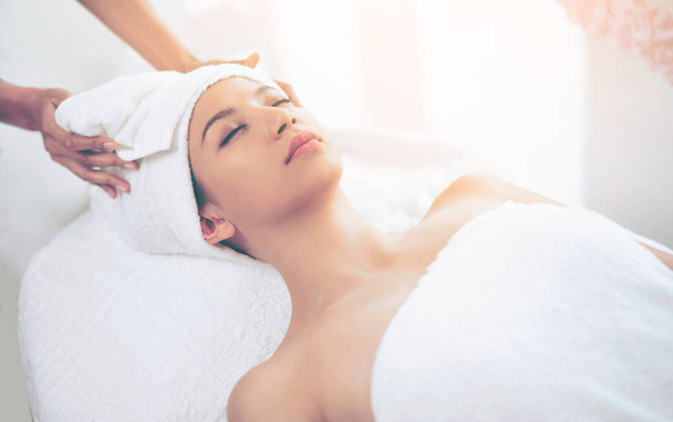 Relaxed young woman lying on spa bed prepared for facial treatment and massage in luxury spa resort. Wellness, stress relief and rejuvenation concept. - Фото, изображение
