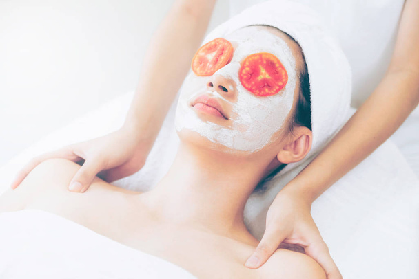Belle femme ayant un traitement de masque facial avec extrait de crème de tomate montrant le bénéfice du traitement de la nature. Cosmétologie anti-âge, soin du visage et style de vie luxueux
. - Photo, image