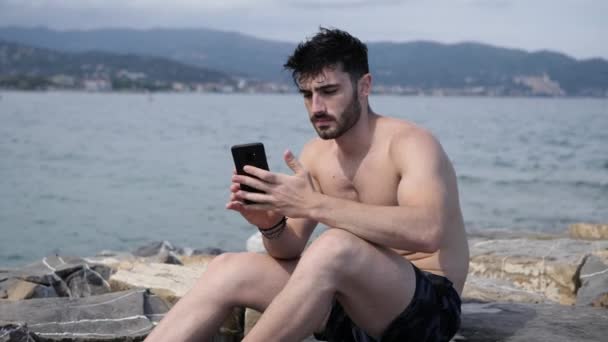 Fiatal ember használ sejt telefon, a film a tengerre tengerparton - Felvétel, videó