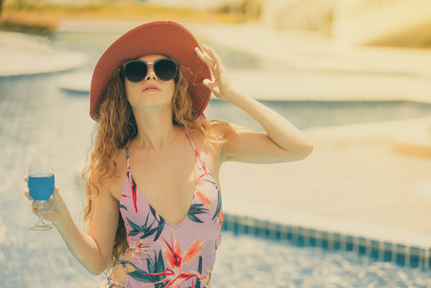 Mujer joven y feliz con traje de baño pasar un buen rato en la piscina en el complejo de lujo. Concepto de vacaciones de verano
. - Foto, imagen