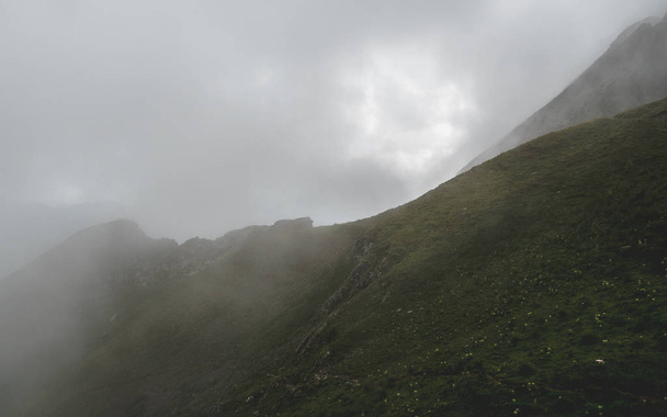 scary hiking path in the fog on steep mountain. hiking path through grass, brienzer rothorn switzerland - Φωτογραφία, εικόνα