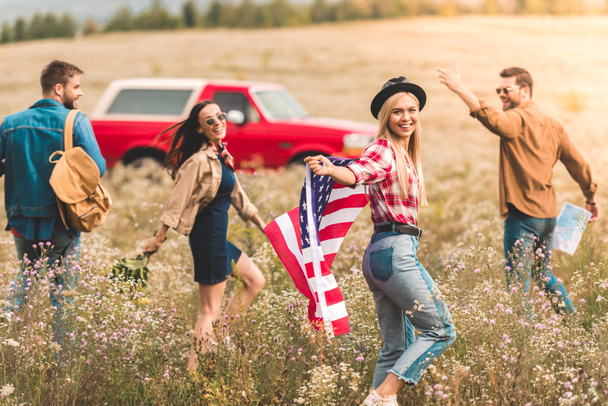groupe de jeunes voyageurs américains heureux avec drapeau marchant par champ de fleurs
 - Photo, image
