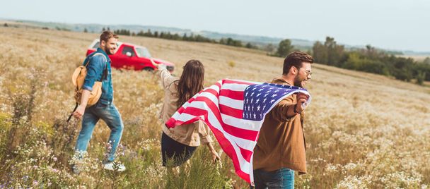 groupe d'amis avec drapeau des États-Unis dans le champ de fleurs pendant le voyage en voiture
 - Photo, image