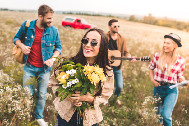 groupe de jeunes marchant par champ avec guitare et bouquet de fleurs
 - Photo, image
